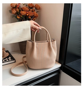 Detailed view of pleated texture on light brown bucket bag with detachable shoulder strap