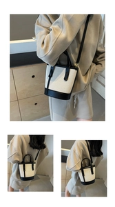 Detail of contrast canvas bucket bag showing beige texture and black leather handles