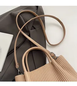 Detail of light brown pleated texture handbag with silver metal hooks and slim strap