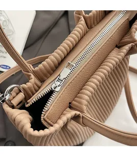 Detail of silver metal zipper closure on brown pleated leather bucket bag