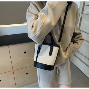 Detail view of contrast bucket bag in canvas and black leather with gold hardware