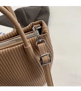 Detail of brown pleated leather bucket bag with silver zipper and detachable strap