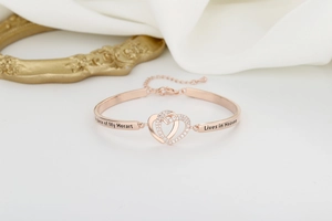 Macro detail of rose gold heart bracelet with infinity symbol and memorial engraving