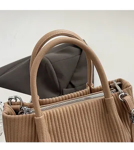 Close-up of pleated beige bucket bag showing lychee grain leather and silver hardware