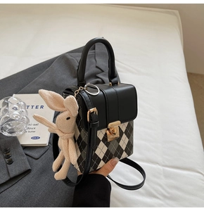 Détail du sac à damier avec serrure dorée vintage et un pendentif lapin en tricot