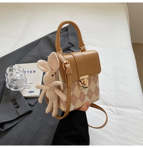Détail du sac bandoulière à losanges roses avec fermoir doré et breloque lapin tricoté