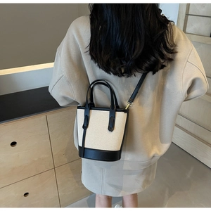 Detail view of contrast bucket bag with canvas body and black leather trims on model