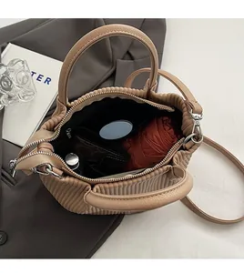 Spacious interior of beige pleated bucket bag showing capacity for umbrella and mirror