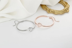 Detail of silver and rose gold heart bracelets with zircons and engraved lettering