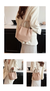 Detail view of beige pleated bucket bag showing vertical folds and shoulder strap