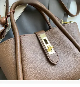 Close-up of brown litchi pattern leather bucket bag with gold lock and chain hardware