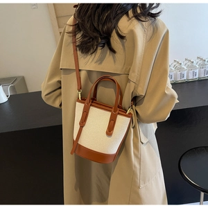 Model shot showing minimalist canvas and brown leather bucket bag on shoulder in modern interior