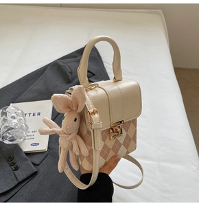 Détail du sac bandoulière à motif losanges rose avec fermoir doré et breloque lapin