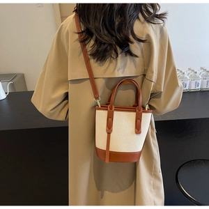 Detail of contrast stitching on canvas bucket bag with brown leather handles and strap
