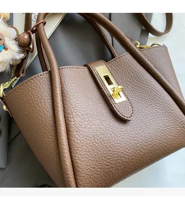 Close-up of brown litchi pattern leather bucket bag with golden twist lock and bear charm