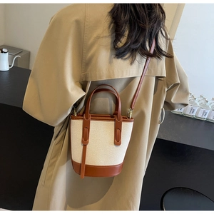 Canvas and leather bucket bag detail on a model wearing a khaki trench coat