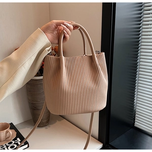 Close-up of beige pleated bucket bag texture with double handles and slim strap