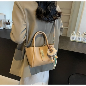 Brown lychee leather bucket bag with lion charm shown on model in a cozy cafe setting