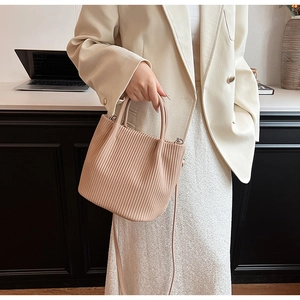 Detailed view of pale pink pleated bucket bag with vertical textures and metal hardware