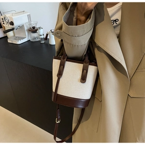 Detailed view of a canvas and leather bucket bag with adjustable strap and golden hardware