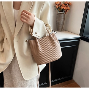 Detail of apricot pleated bucket bag with fine vertical texture and slim shoulder strap