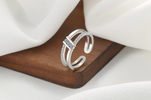 Macro detail of silver double-layered open ring with sparkling cubic zirconia on wood