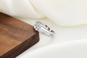 Macro shot of double-layer silver ring with four sparkling zircons on walnut wood