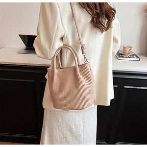 Detail of pleated beige bucket bag with round handle in a modern lifestyle setting