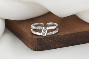 Macro detail of silver double-layer open ring with sparkling cubic zirconia on wood