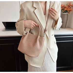 Detailed view of beige pleated bucket bag with vertical textured synthetic leather