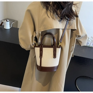 Detail of contrast color bucket bag in beige canvas and brown leather on model