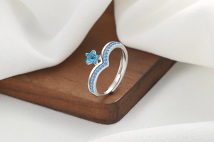Macro shot of silver star ring with blue crystals on a textured wooden and fabric surface