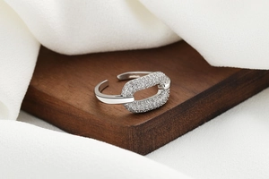 Macro shot of silver adjustable ring with pavé cubic zirconia oval link on wood