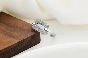 Macro shot of a silver geometric chain ring featuring pavé-set cubic zirconia on silk