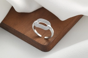 Macro detail of silver adjustable open ring with micro-paved cubic zirconia on wood pedestal