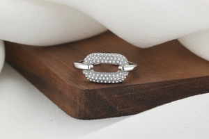 Detailed macro view of silver geometric ring with pavé-set zircons on dark wood