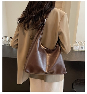 Detail of dark brown leather hobo bag showing texture and adjustable shoulder strap