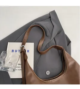 Close-up of brown crescent underarm bag with adjustable shoulder strap and silver buckle
