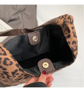 Detail of the golden magnetic snap closure and leopard print lining on the tote bag
