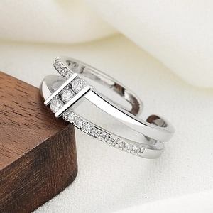 Double-layer silver open ring with cubic zirconia accents on a dark wood background