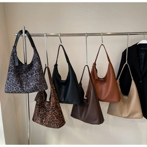 Multiple vintage tote bags in leopard print and solid leather colors on display hooks