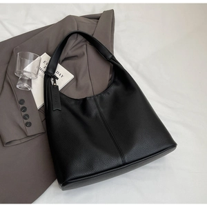 Detail of black pebble grain leather tote bag showing vertical stitching and texture
