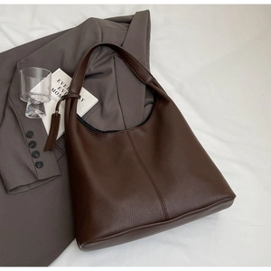 Detailed view of dark brown tote bag with litchi grain texture and wide shoulder strap