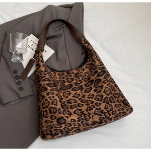 Detailed close-up of leopard print hobo bag with brown leather strap and side tag