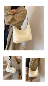Detail of creamy half-moon tote bag with quilted texture and silver chain strap