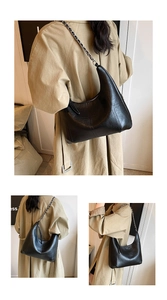 Detail of black crescent shoulder bag featuring lychee texture and silver chain strap