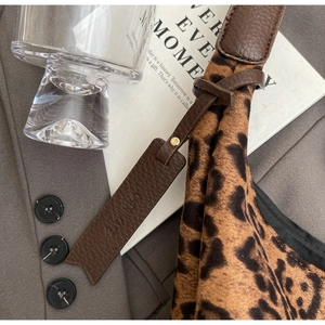 Detailed close-up of leopard print tote bag fabric with leather strap and metal charm