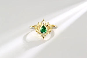 Dettaglio di un anello a loto con gemma verde a goccia e zirconi brillanti
