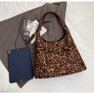 Detail of leopard print tote bag with brown leather handles on office attire background