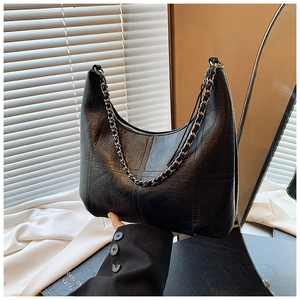 Close-up of black leather hobo bag with distinctive silver chain and textured stitching